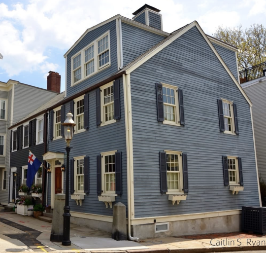 2 1/2 story wood clapboard house with side gable roof and stone foundation